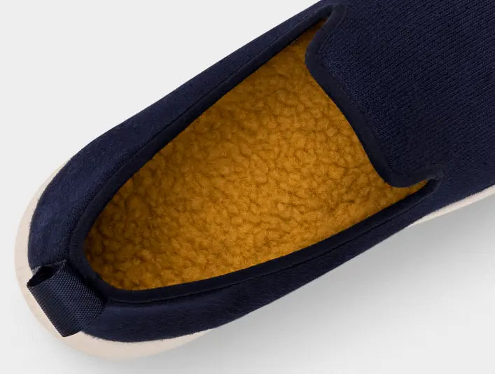 Blue slip-on shoes  on grey background showing sole of yellow color