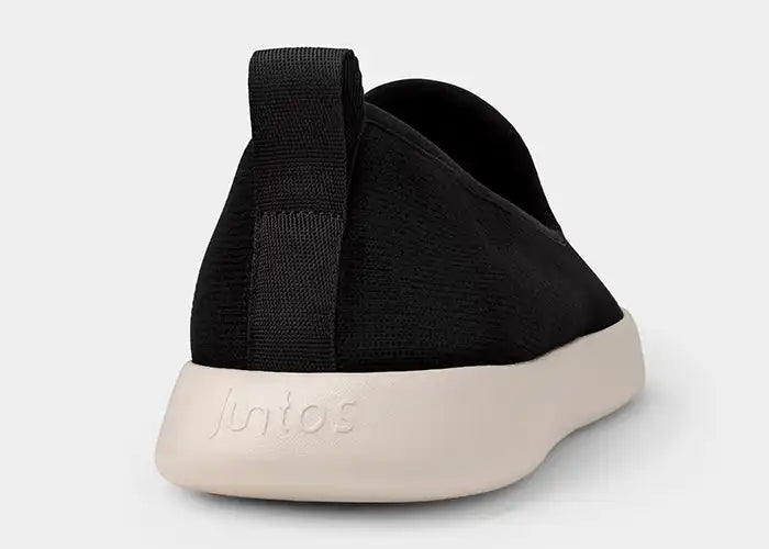 Black slip-on sneaker with a white sole on a light gray background