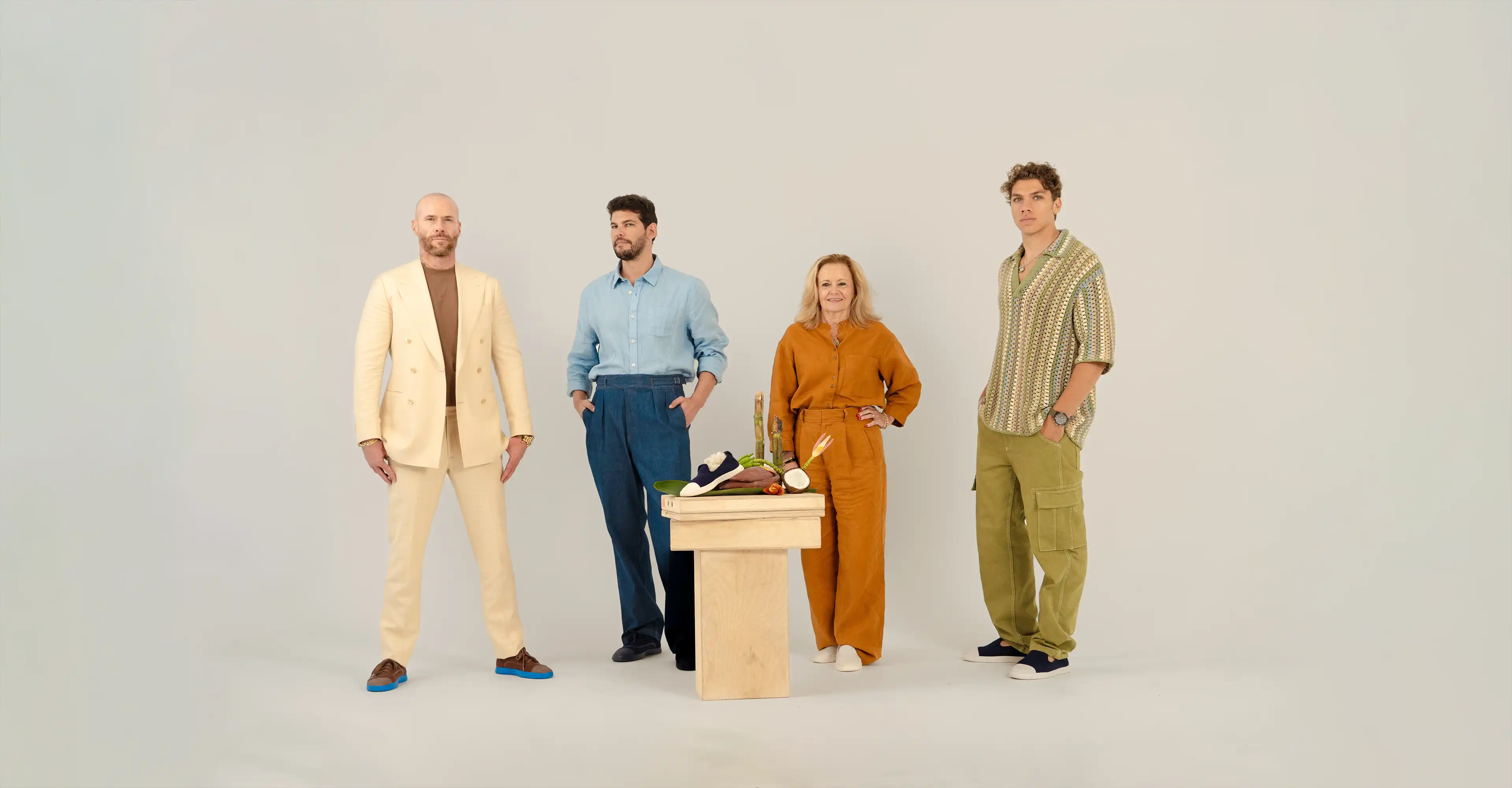 Four people standing around a table with a neutral background