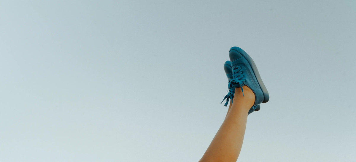 Blue athletic shoe being lifted against a light blue background