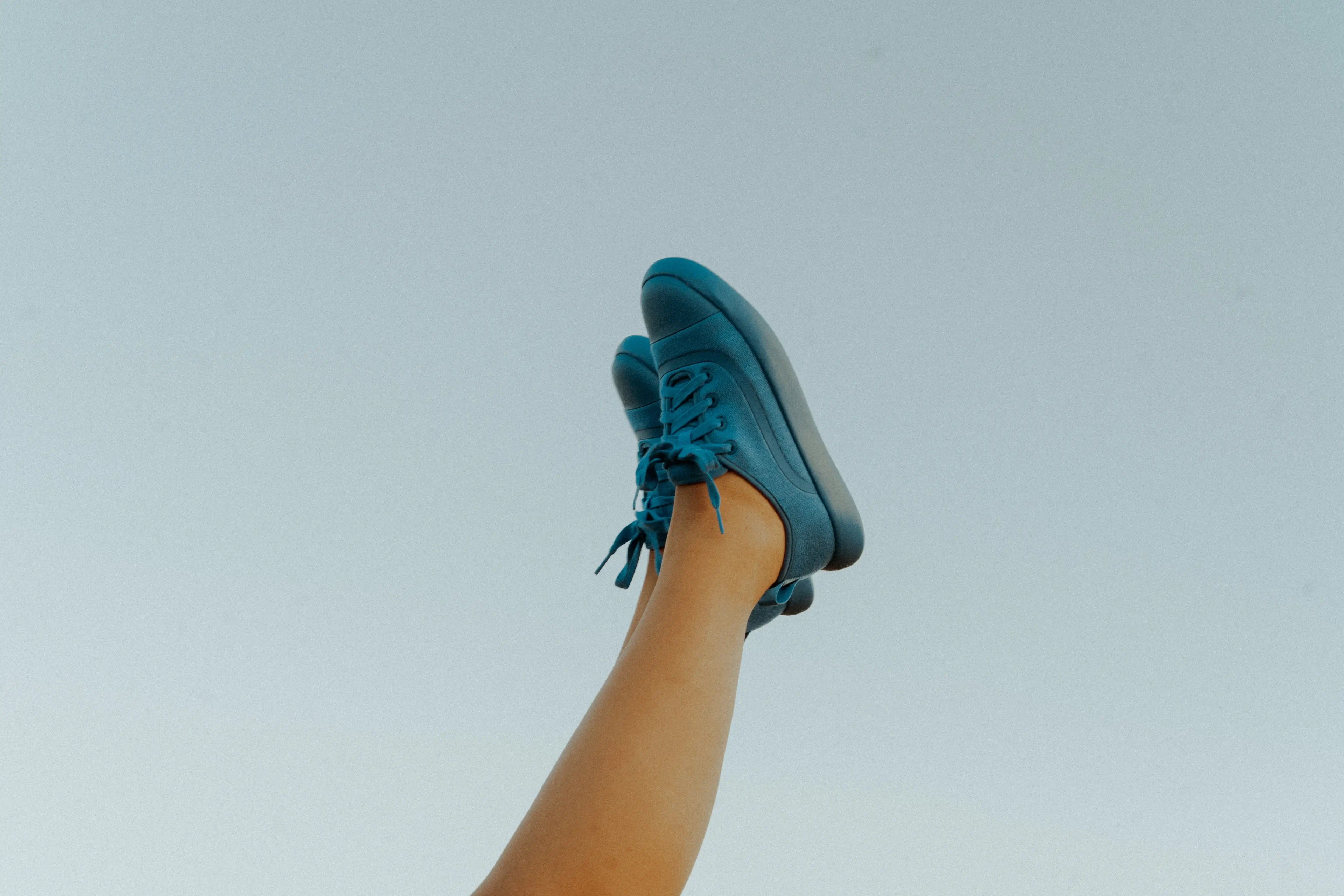 Person wearing teal sneakers against a light blue background