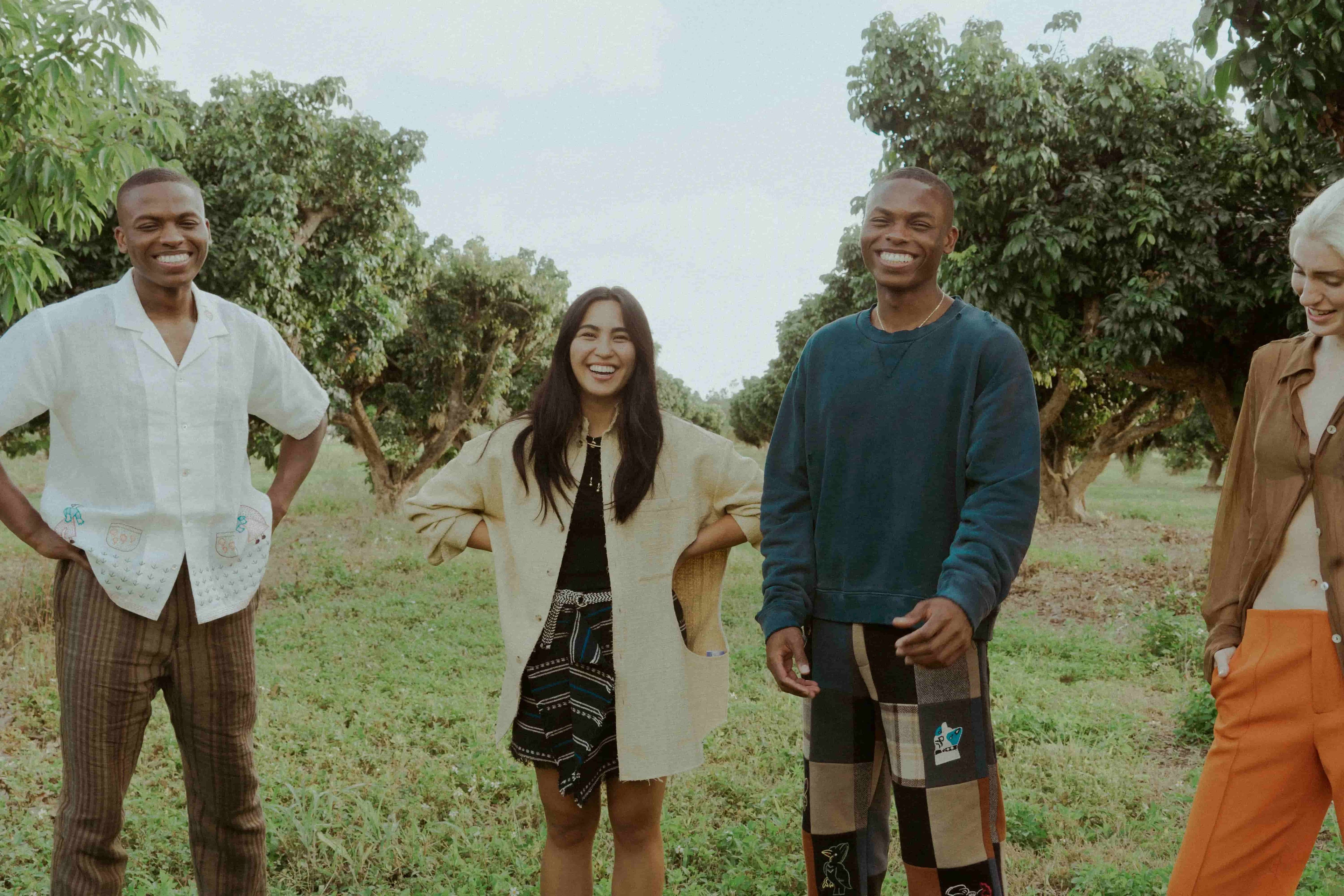 Four people standing together in a natural setting with trees in the background