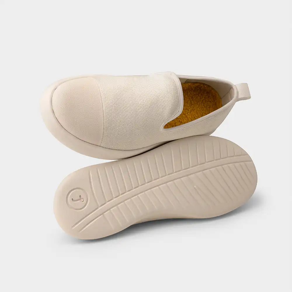 Beige slippers with a textured sole on a light gray background